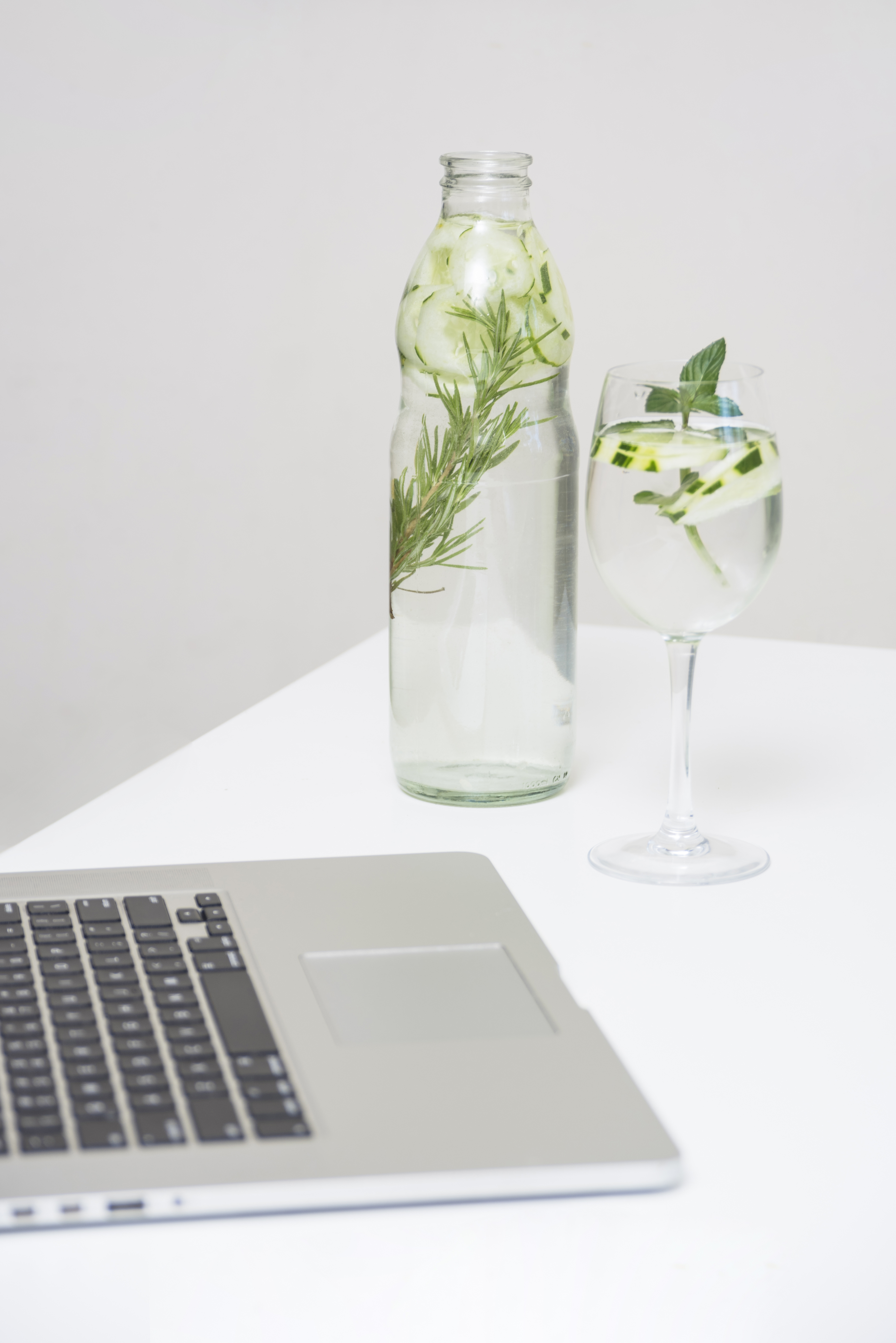 Stay Hydrated: Glass Water Bottle on Desk A clear glass water bottle placed on an office desk, reminding to stay hydrated during work.